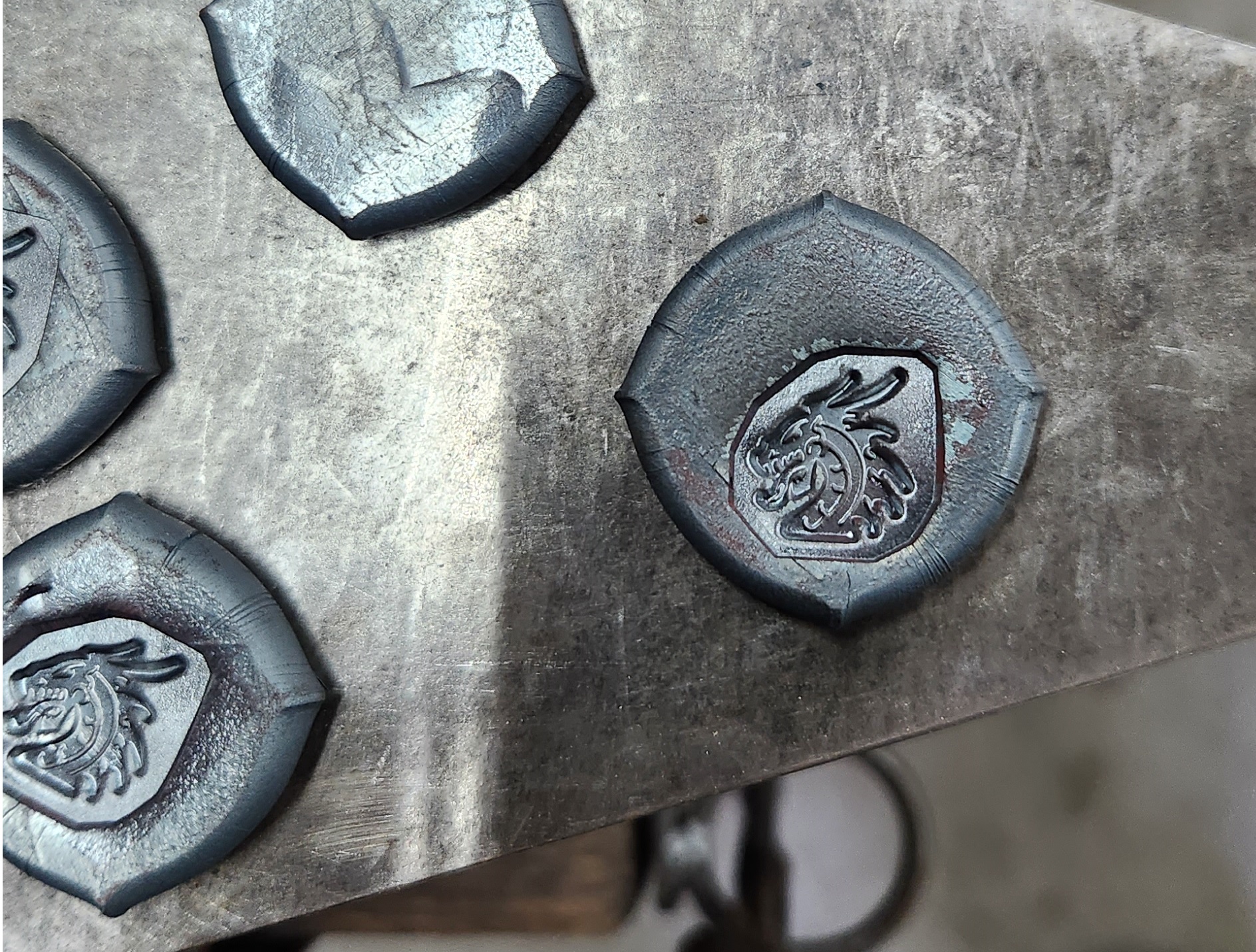Hand-stamped iron dragon medallions on the anvil.