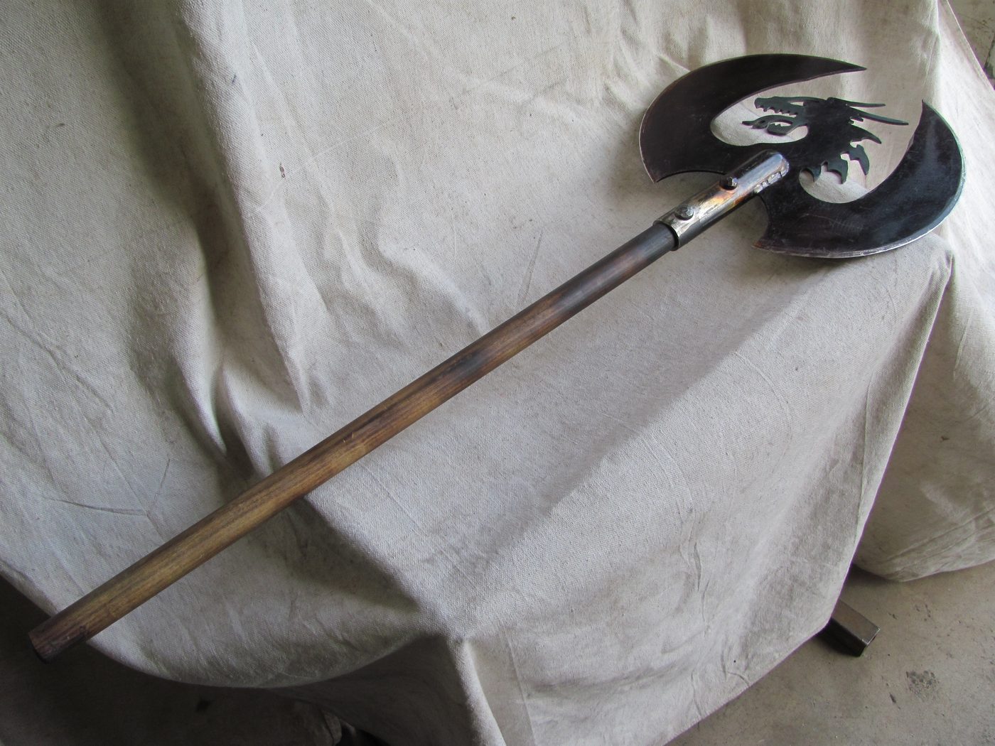 Hand-forged battle axe with a dragon silhouette cut through the blade.