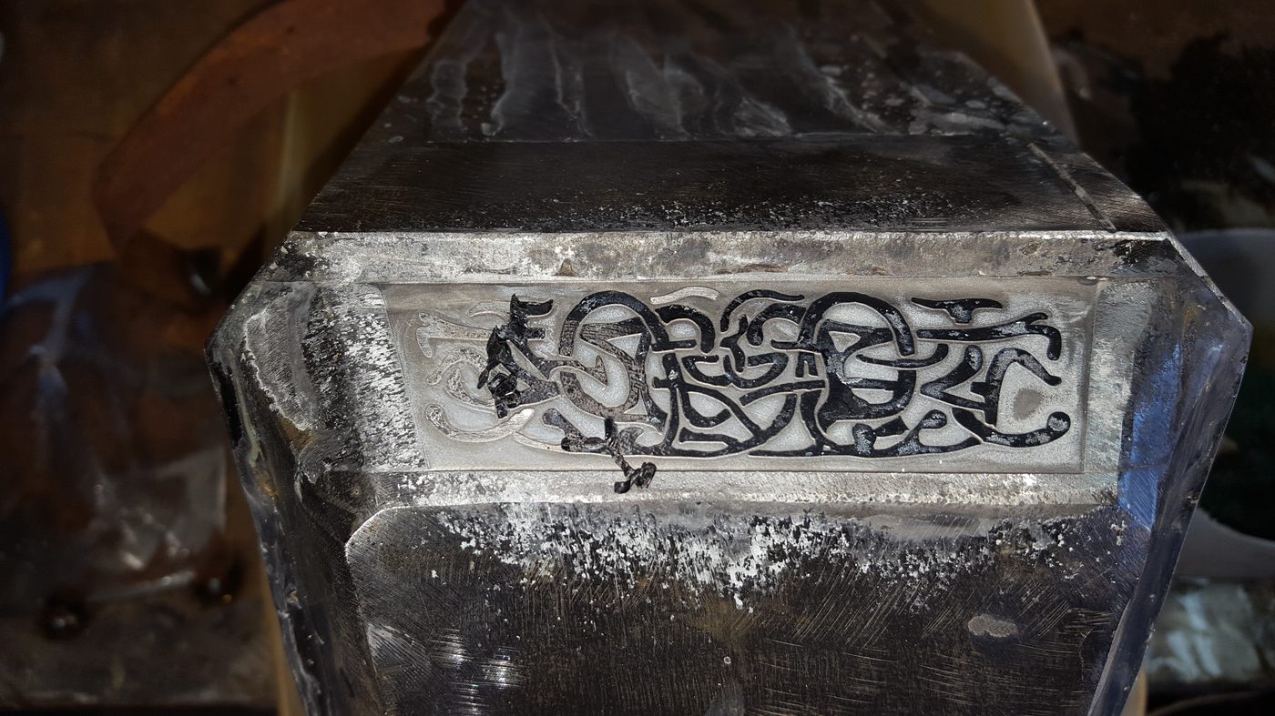 Close-up of the engraved Celtic knotwork chiseled into the face of a hand-forged Mjolnir.