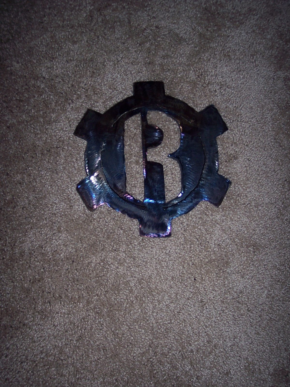 Forged steel emblem with heat-tempered iridescent finish.